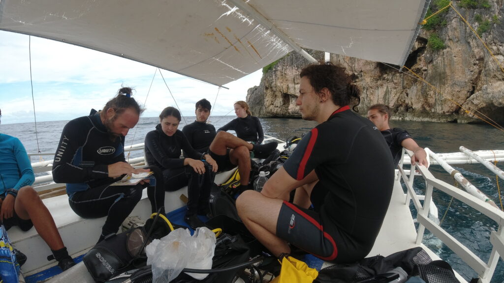 On a boat, with a guy holding a small book teaching.