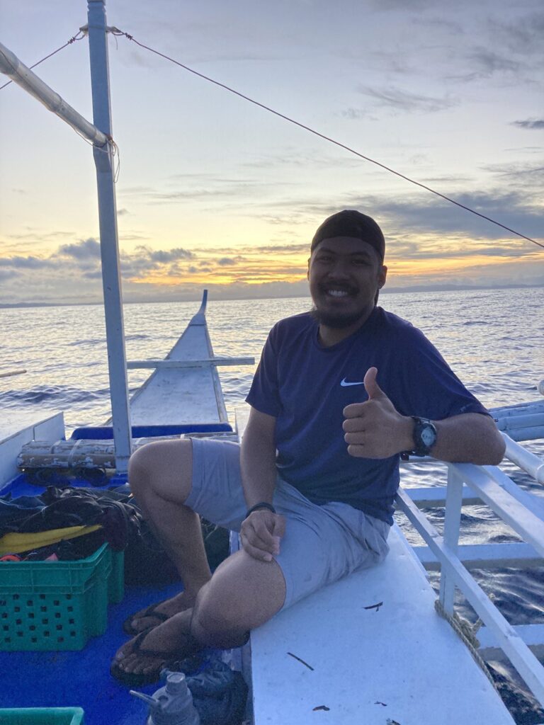 Picture of a man on a boat with the sunrise as the background