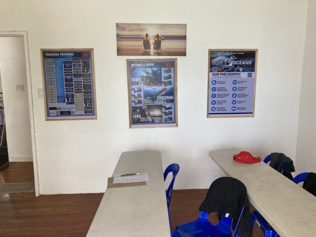 A table and chairs with some postings on the wall