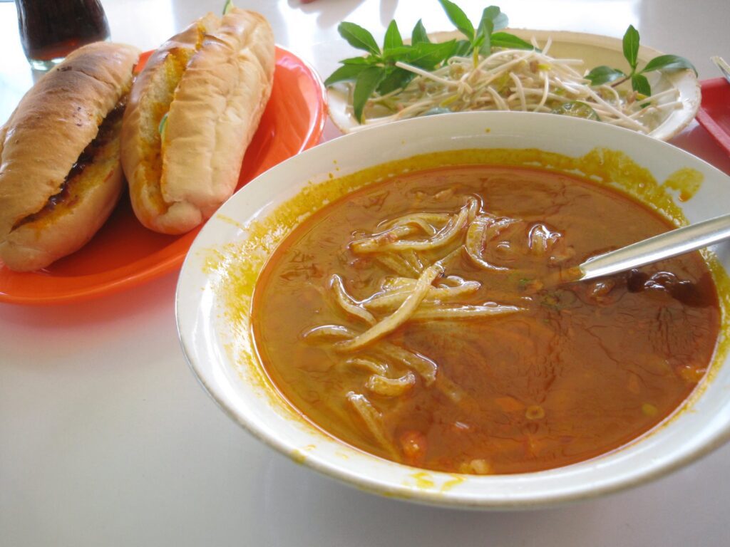 A soup, bread and bean sprouts.