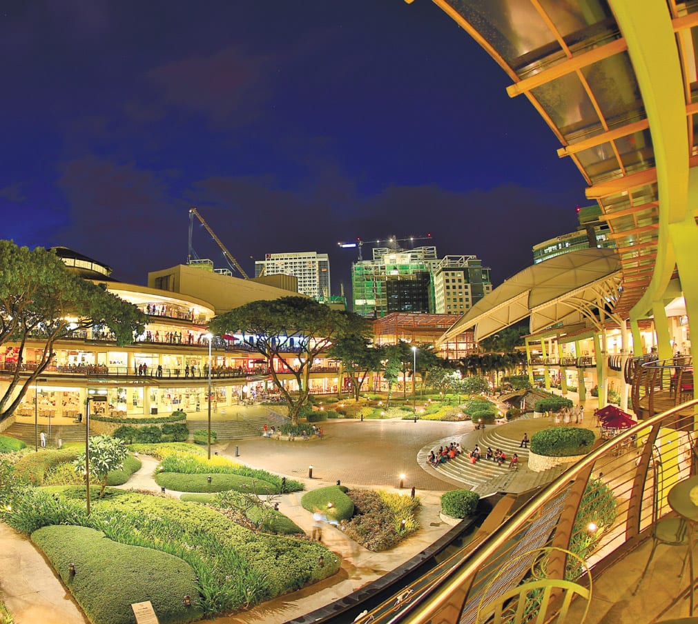 A wide garden surrounded by shops and restaurants.