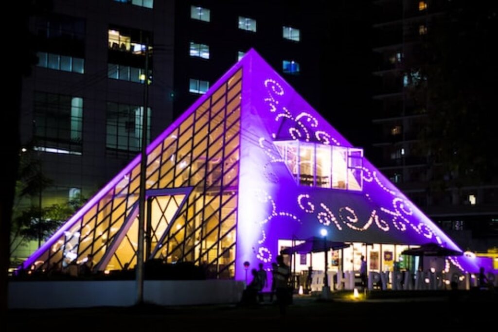 A pyramid-shaped restaurant shot at night with violet light.