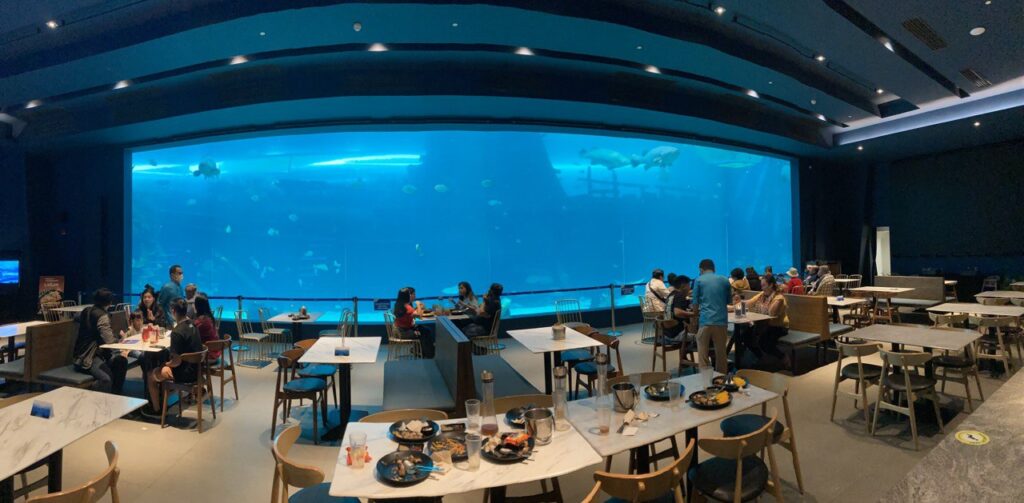 People dining with an enormous aquarium in the background.