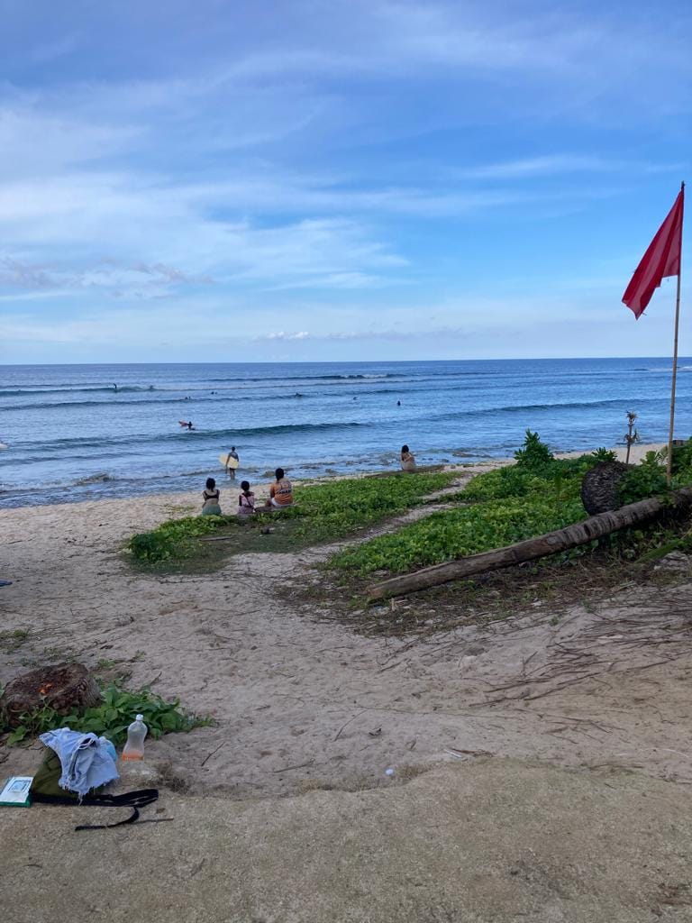At the Pacifico beach. People sitting by the shores while surfers are riding in the waves. 