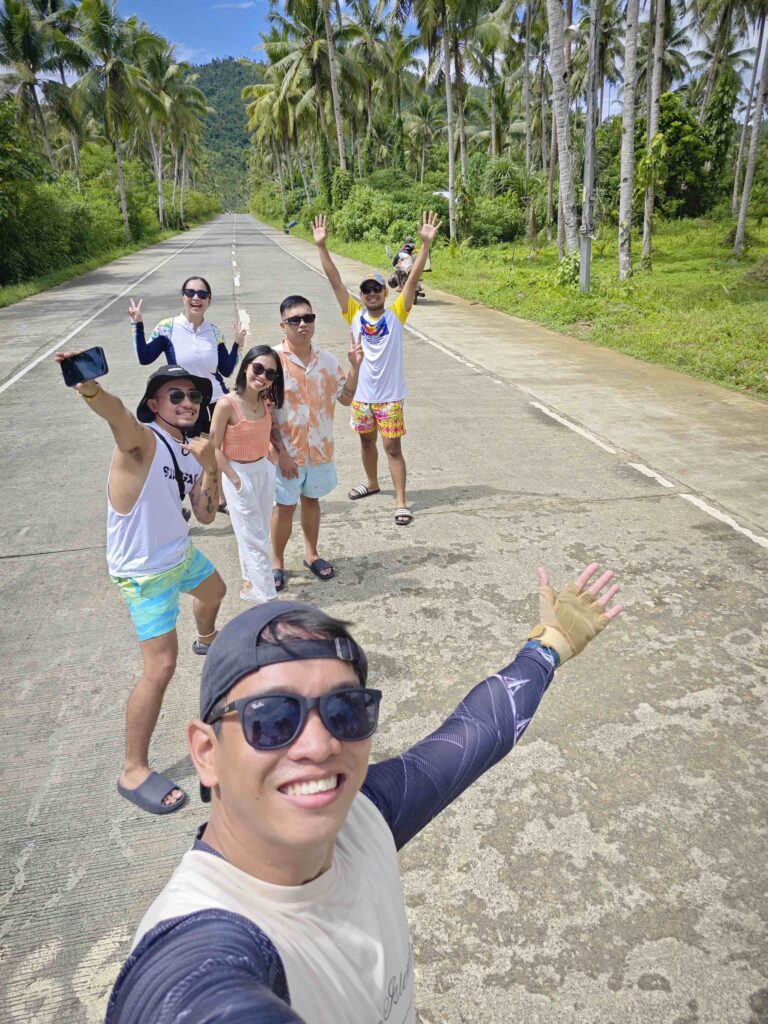 six people taking a picture on the middle of the road.