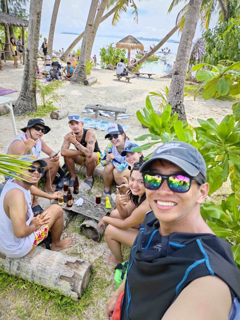 people taking a picture while drinking beer on the beach. 